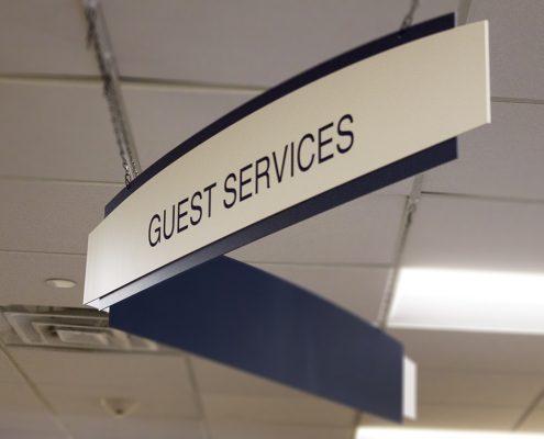 Double paneled suspended Guest Services sign
