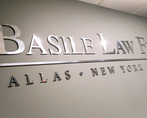 chrome lettering on an interior wall reading Basile Law Firm Dallas New York Naples